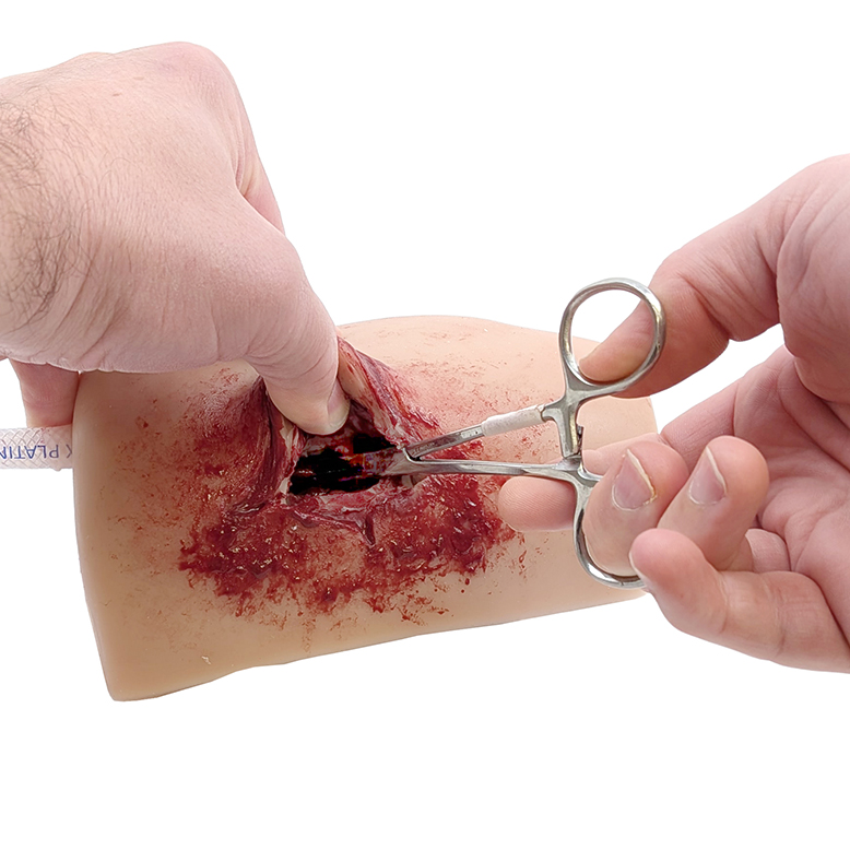 Clamping the bleeding vessel inside the TrueClot TnT Task Trainer exit wound with a hemostat